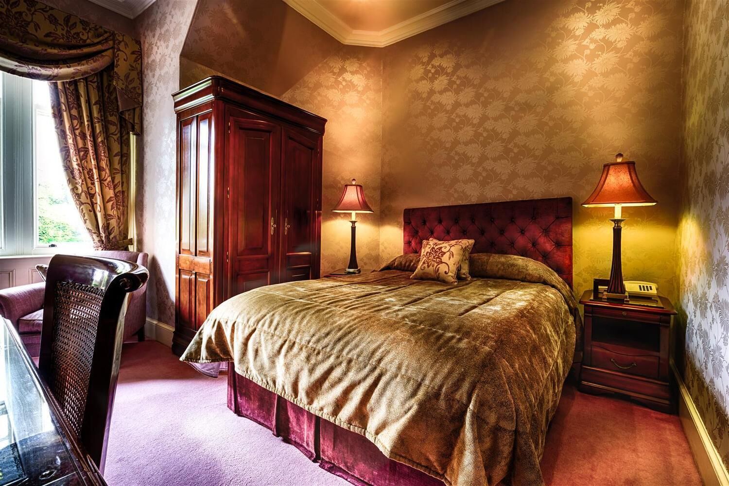 Un dormitorio con una cama grande, dos lámparas de noche, un armario de madera y una silla.
