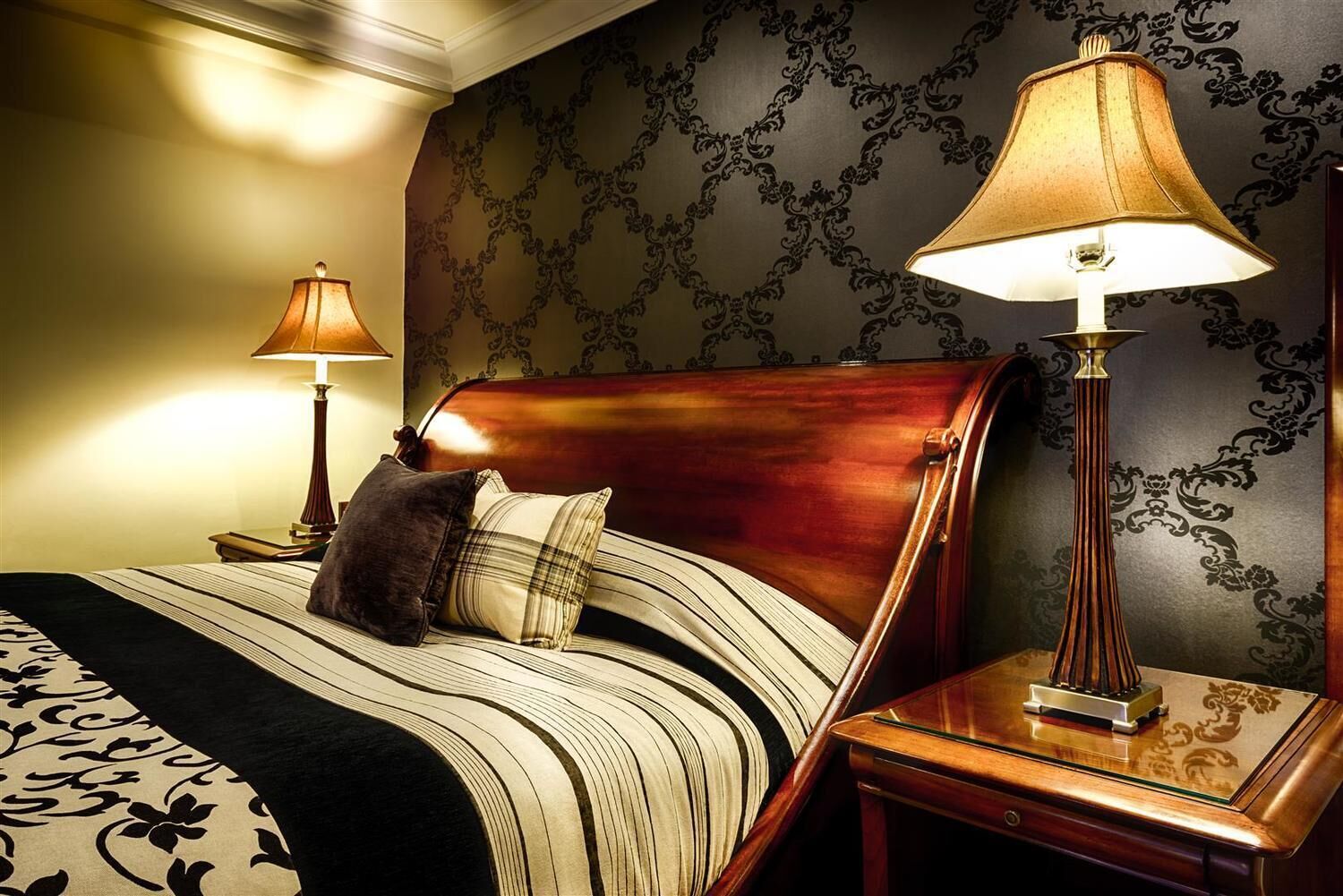 A hotel room with a bed, two bedside lamps, a nightstand, and a decorative wall.