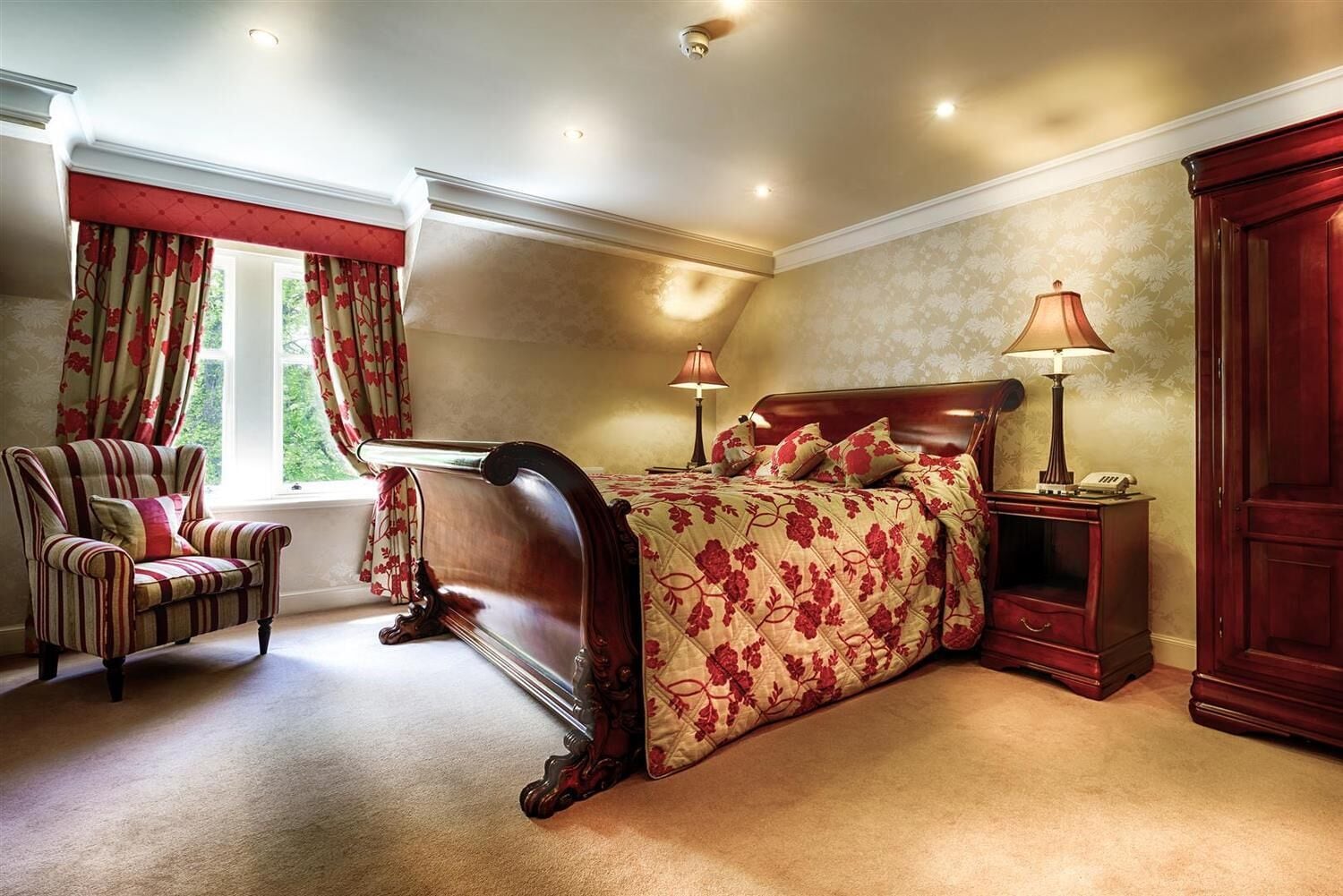 A bedroom with a large bed, a chair, a nightstand, and a wardrobe.