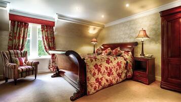 A bedroom with a large bed, a chair, a nightstand, and a wardrobe.