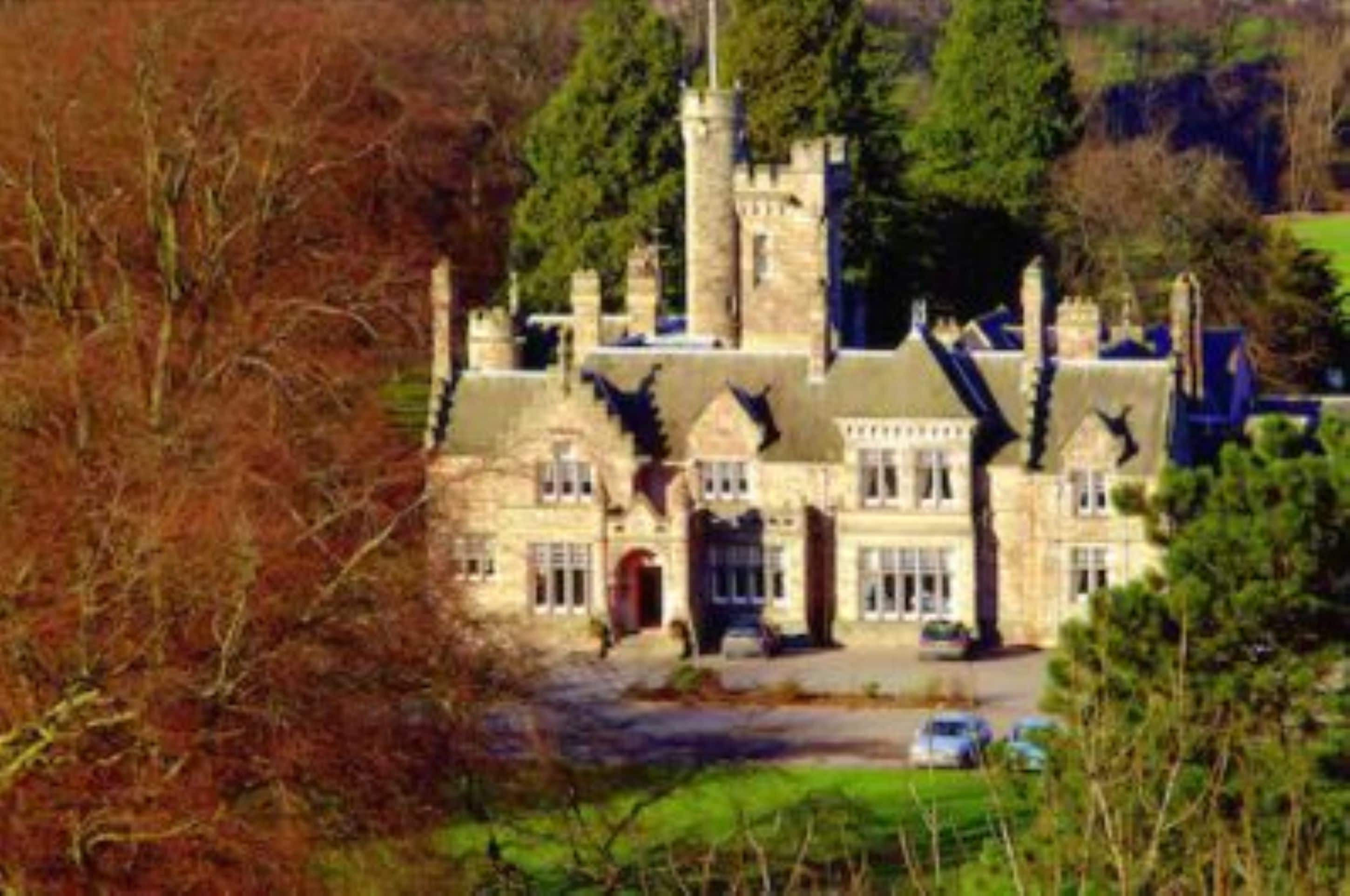 A large, historic stone building with multiple towers and a prominent entrance.