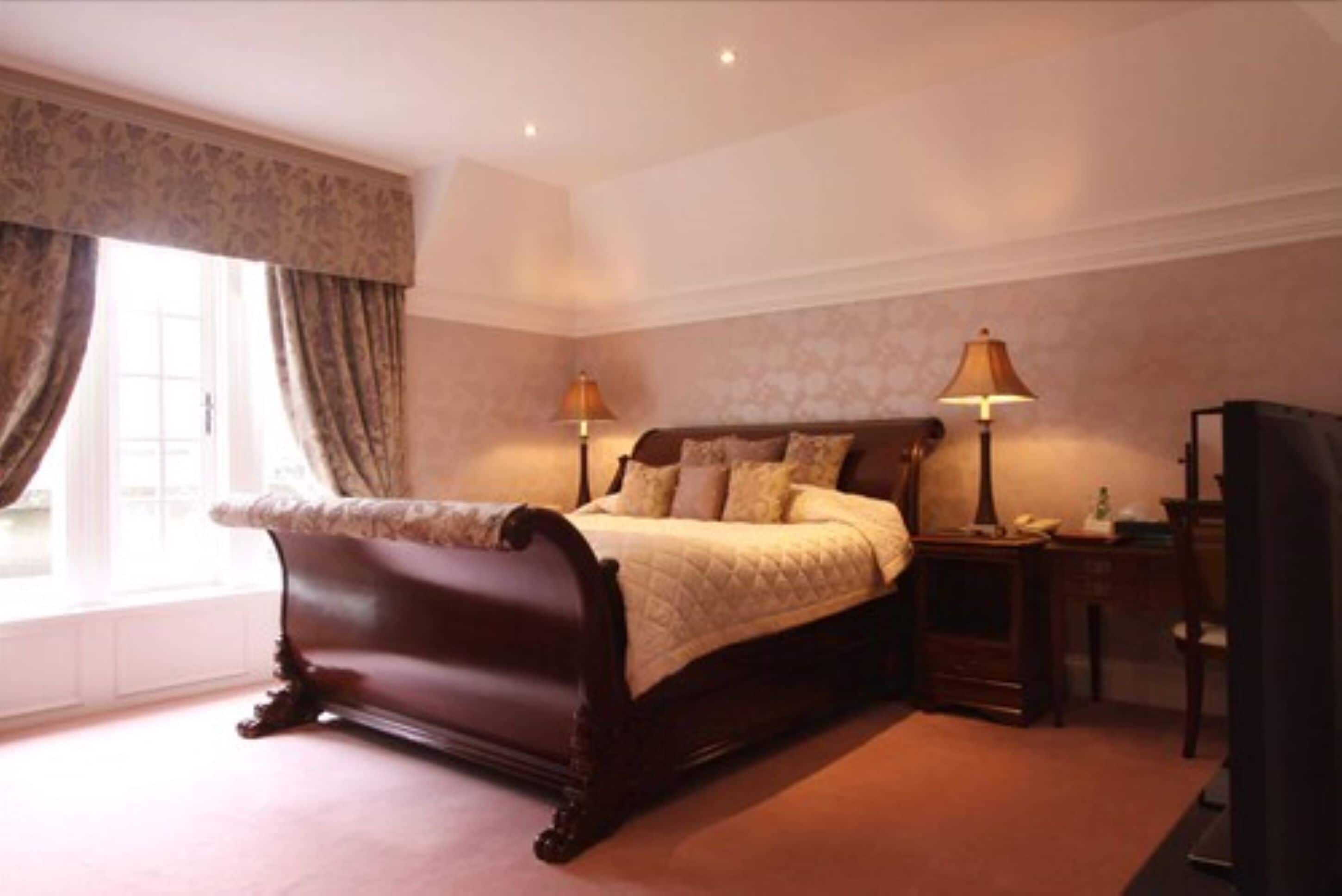 A bedroom with a large bed, two bedside lamps, a nightstand, and a dresser.
