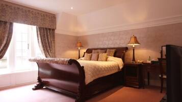 A bedroom with a large bed, two bedside lamps, a nightstand, and a dresser.