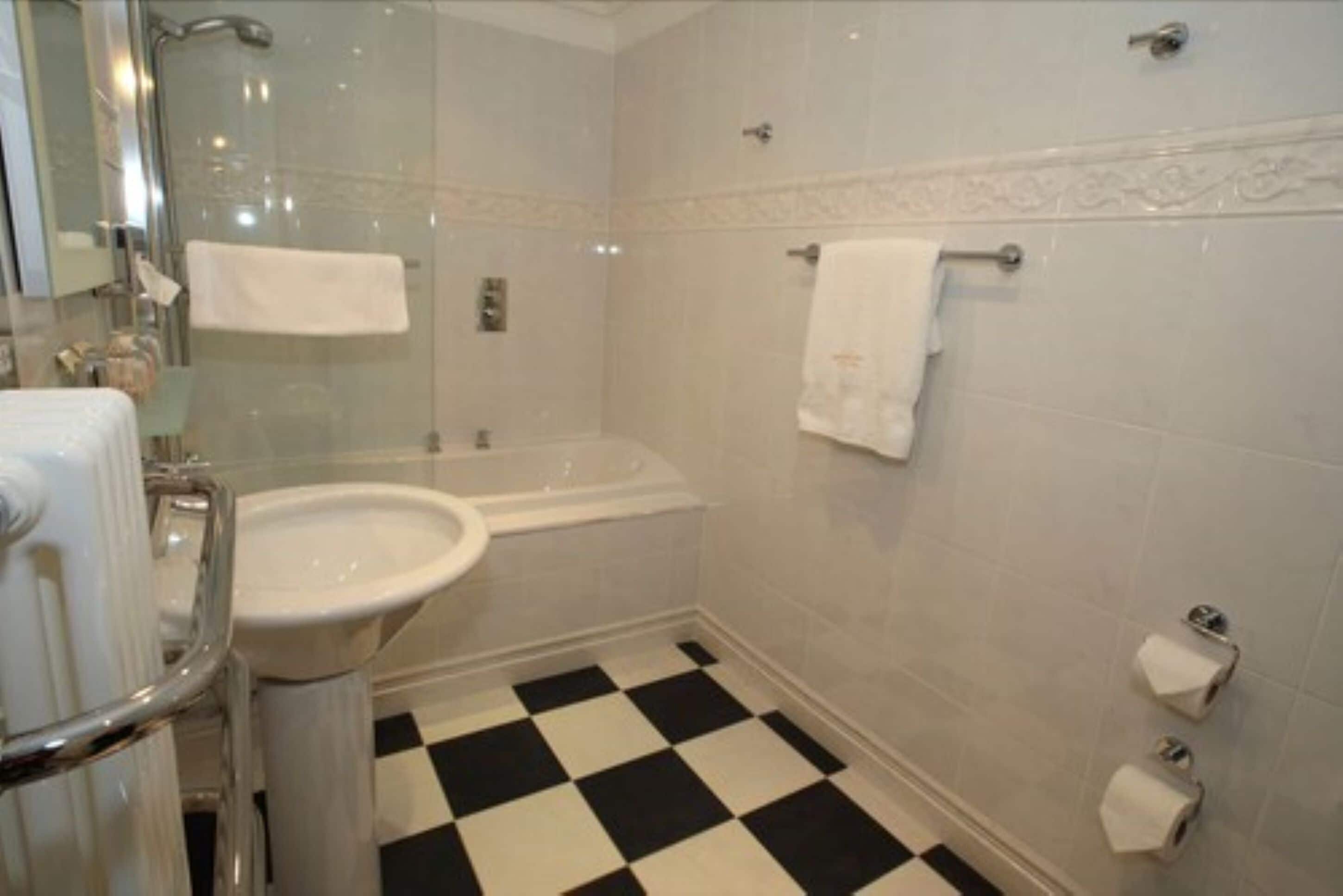A bathroom with a sink, bathtub, and a checkered floor.