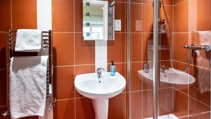 A modern bathroom with a glass shower enclosure, two sinks, and a towel rack. - Old Posting House (Cockermouth)