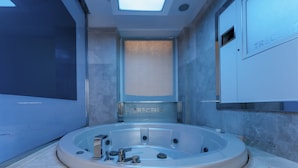 A modern bathroom with a central jacuzzi, a skylight, and a visible brand name on the wall. - Hotel Trecento (Rome)