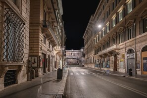 A nighttime street view with historic buildings, a clear road, and a distant view of a grand building. - Hotel Trecento (Rome)