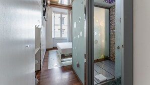 A modern hotel room with a glass partition, wooden flooring, a bed, and a bathroom with a stone wall. - Hotel Trecento (Rome)