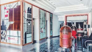 A modern hotel lobby with a geometric patterned floor, a reception desk, and a seating area with a unique bird-shaped chair. - Amelie Hotel Manila (Manila)