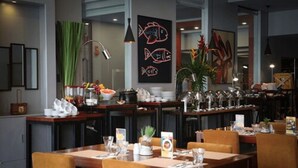 A restaurant with wooden tables and chairs, a chalkboard with fish drawings, and various dishes and utensils on the tables. - Amelie Hotel Manila (Manila)