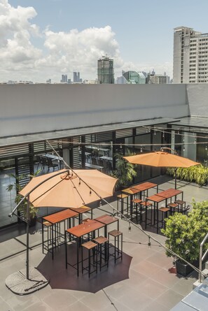 A rooftop terrace with outdoor seating, potted plants, and a city skyline view. - Amelie Hotel Manila (Manila)