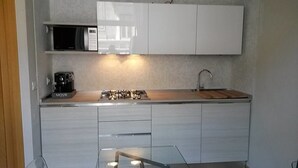 Una cocina moderna con armarios blancos, estufa a gas, microondas y cafetera.