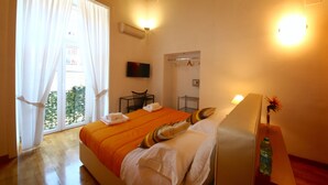 Una habitación de hotel con una cama grande, un escritorio, una silla, un televisor y una ventana con cortinas.