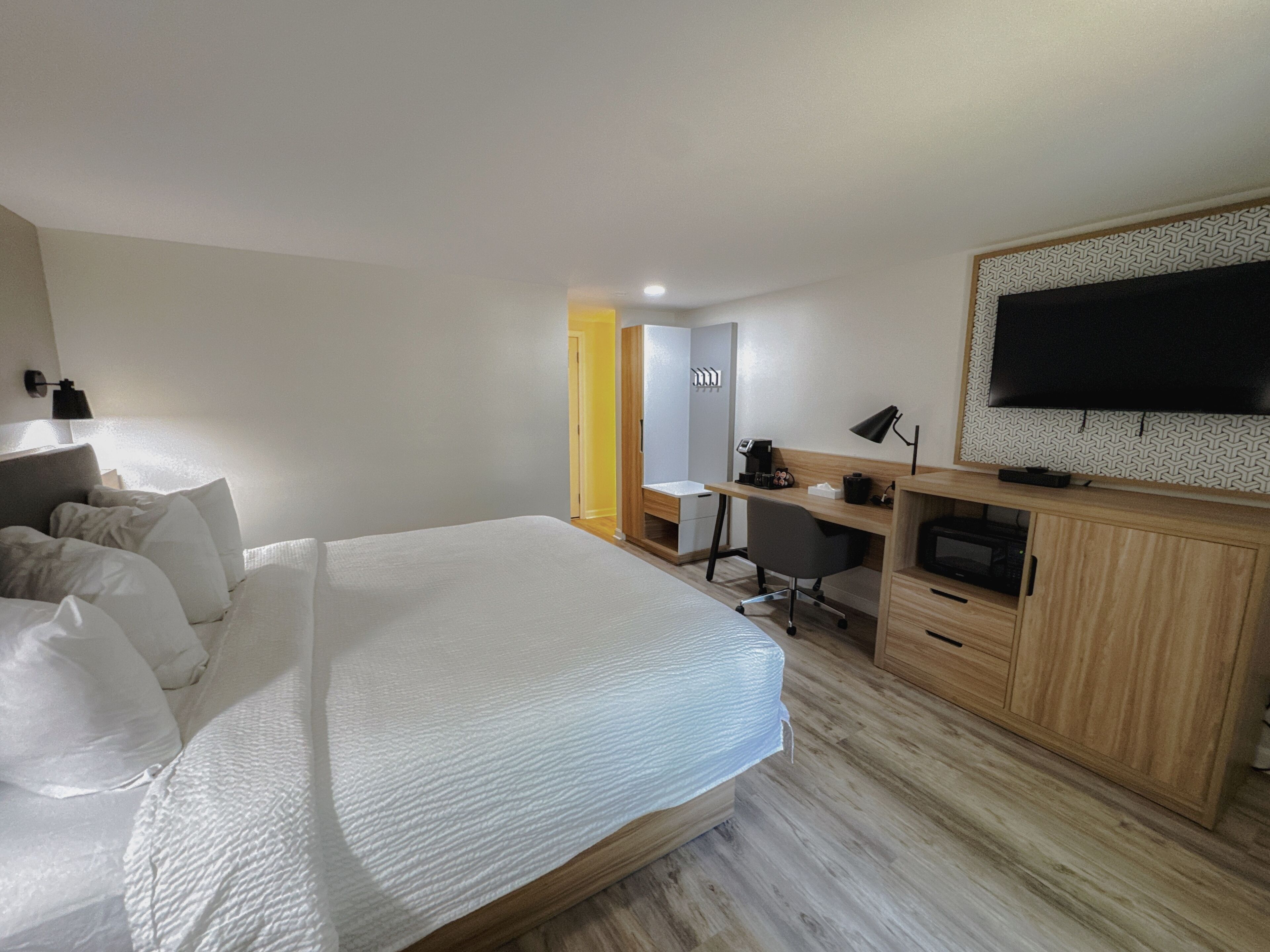 Ein Hotelzimmer mit Bett, Schreibtisch, Stuhl, Fernseher und Kleiderschrank.
