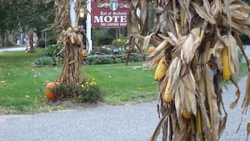 A street scene with autumn decorations, including corn stalks and pumpkins, and a sign for 'Earl of Sandwich Mote The Lantern Shop'.
