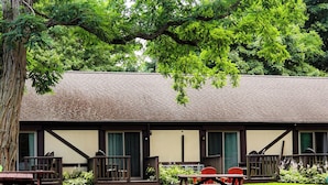 A rustic building with a thatched roof, surrounded by lush greenery and a well-maintained lawn.