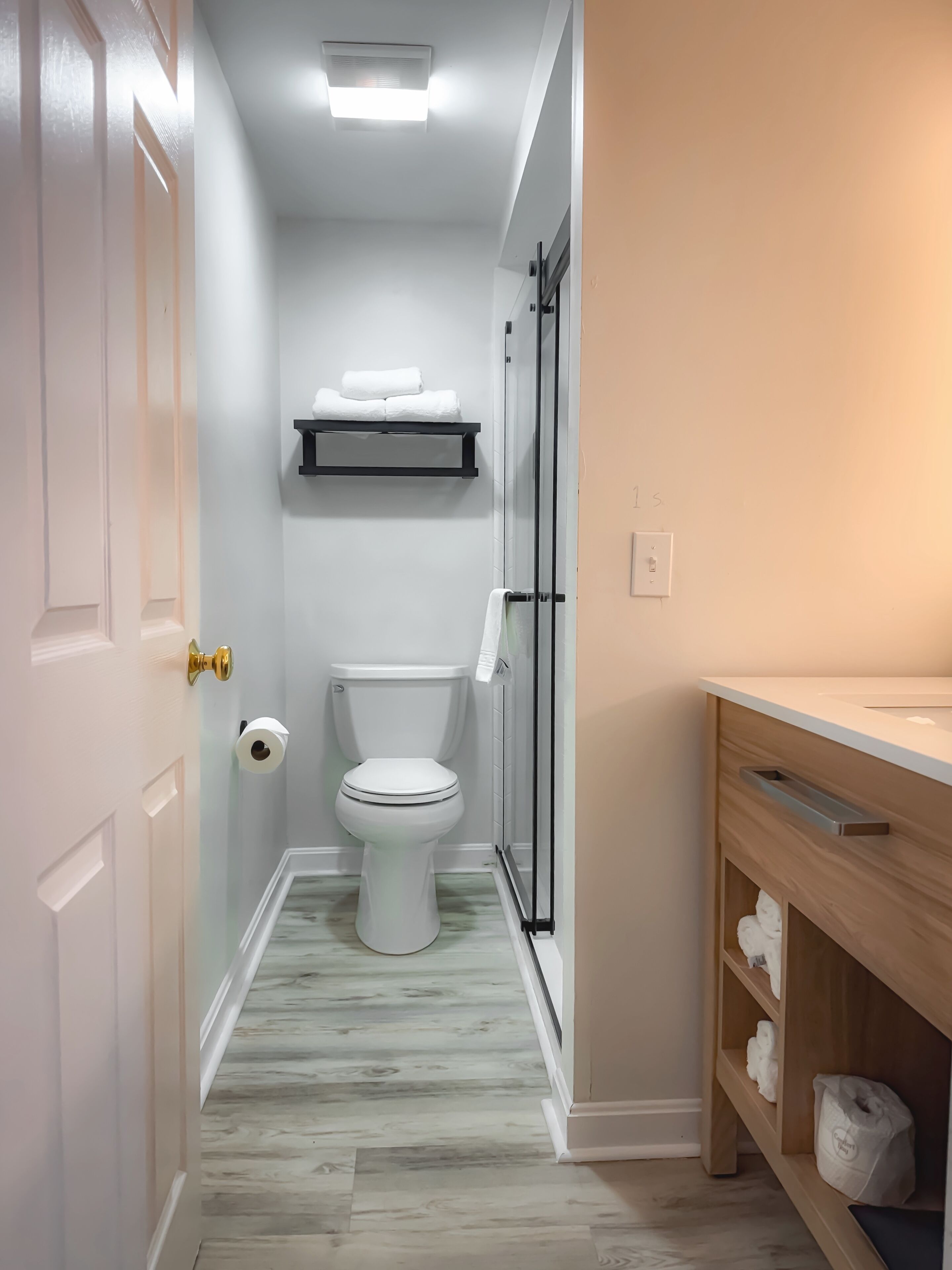 Un baño estrecho con inodoro, ducha y lavamanos.