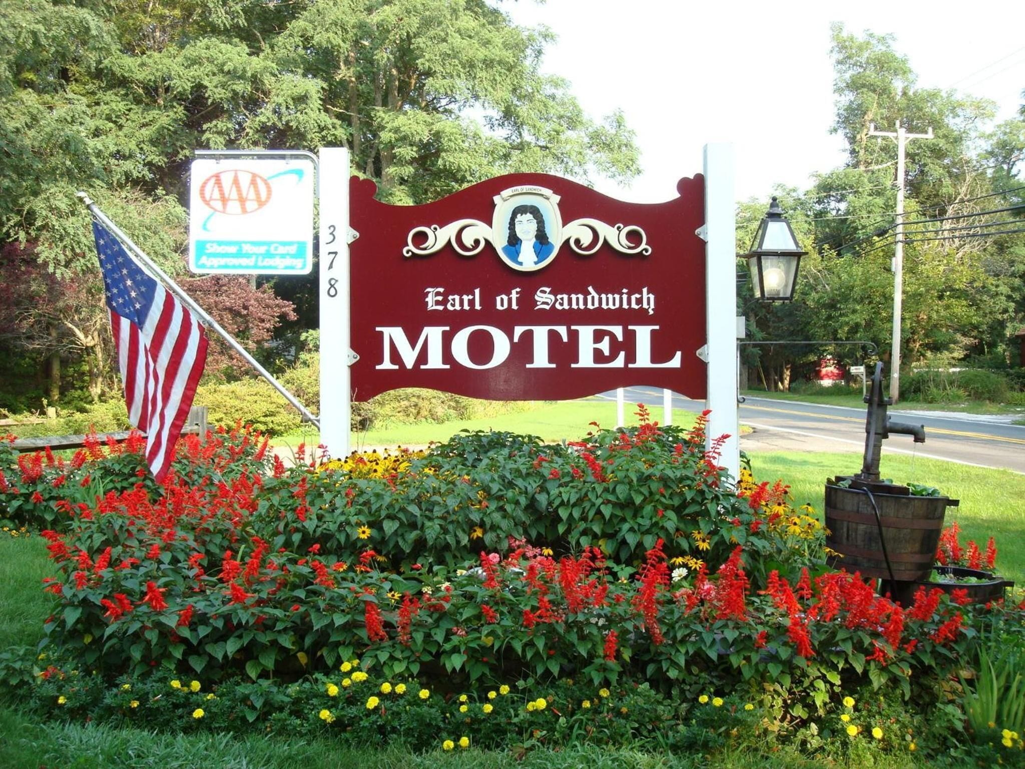 Une enseigne de motel au design rétro, entourée d’un jardin où poussent des fleurs rouges et jaunes.