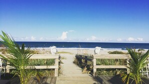 Une promenade en bois qui mène à une plage d’où l’on a une vue dégagée sur l’océan.