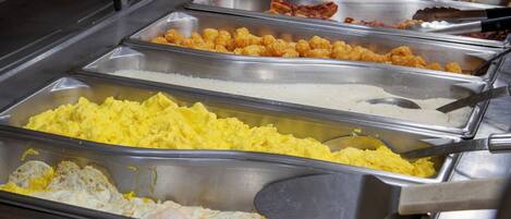 A buffet with various food options including scrambled eggs, fried chicken, and other dishes.