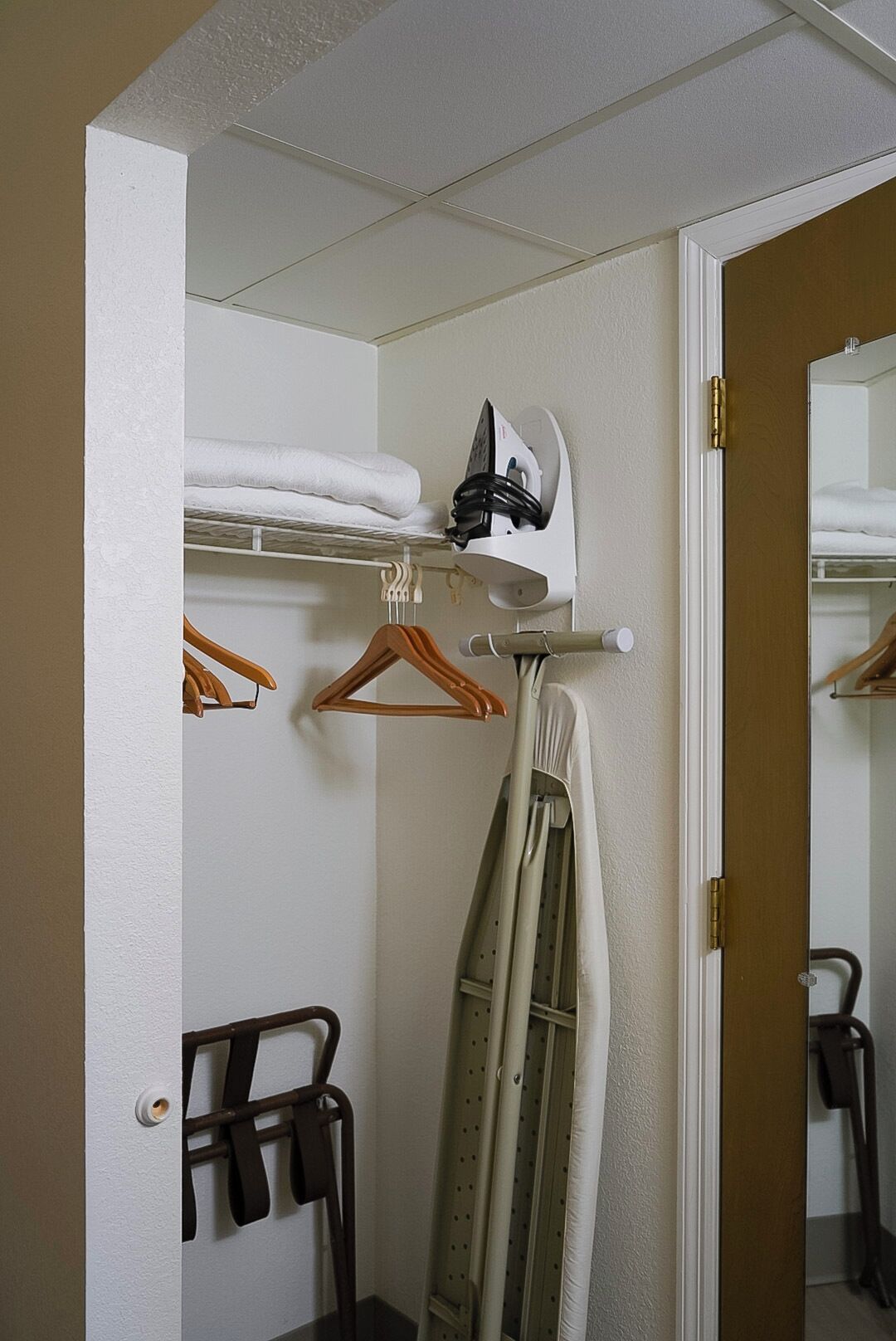 Une chambre d’hôtel équipée d’un lit, d’une planche à repasser, d’un porte-vêtements et d’un miroir.