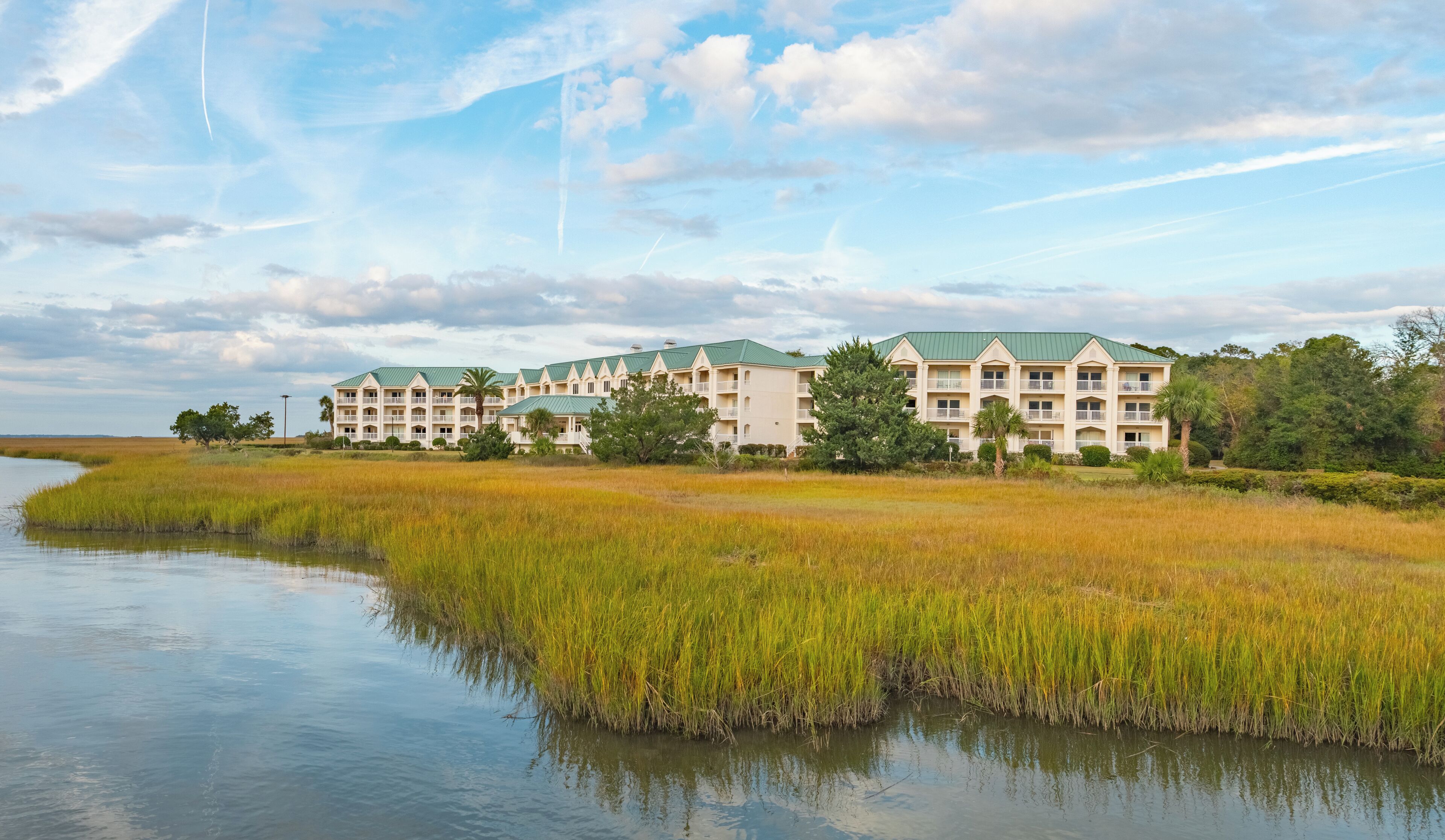 A hotel with multiple buildings, a waterfront, and surrounding marshland.