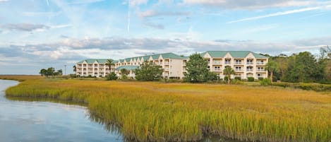 A hotel with multiple buildings, a waterfront, and surrounding marshland.