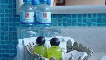 A bathroom with a tiled wall, a mirror, and a basket containing toiletries.