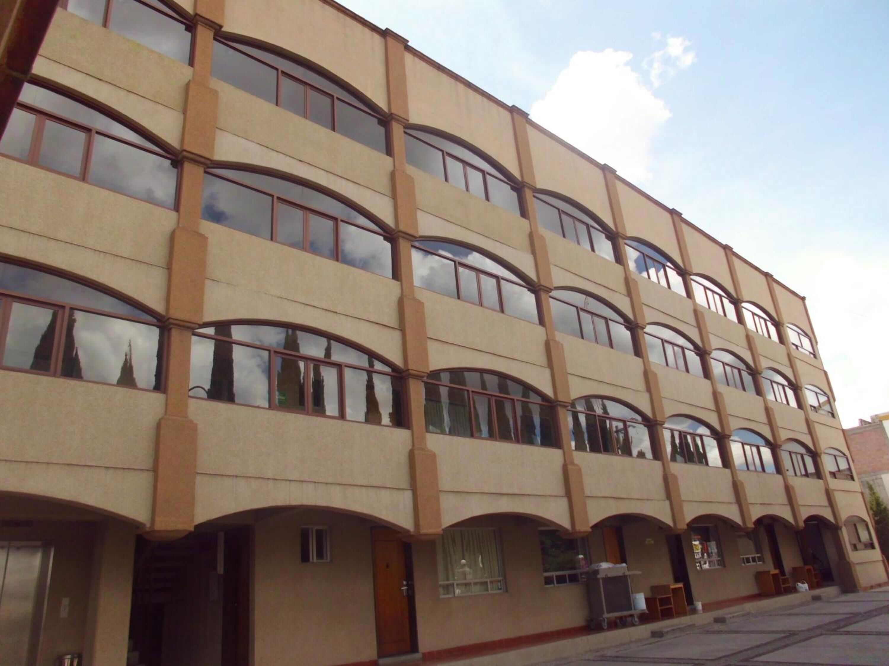 Um edifício de vários andares com fachada simétrica, janelas amplas e telhado plano.