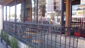 Um edifício com área de estar coberta ao ar livre, grades de metal e jardineiras com grama.
