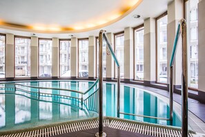 A large indoor swimming pool with clear glass walls, surrounded by windows and a curved ceiling. - Tatrytop Apartamenty Stara Polana (Zakopane)