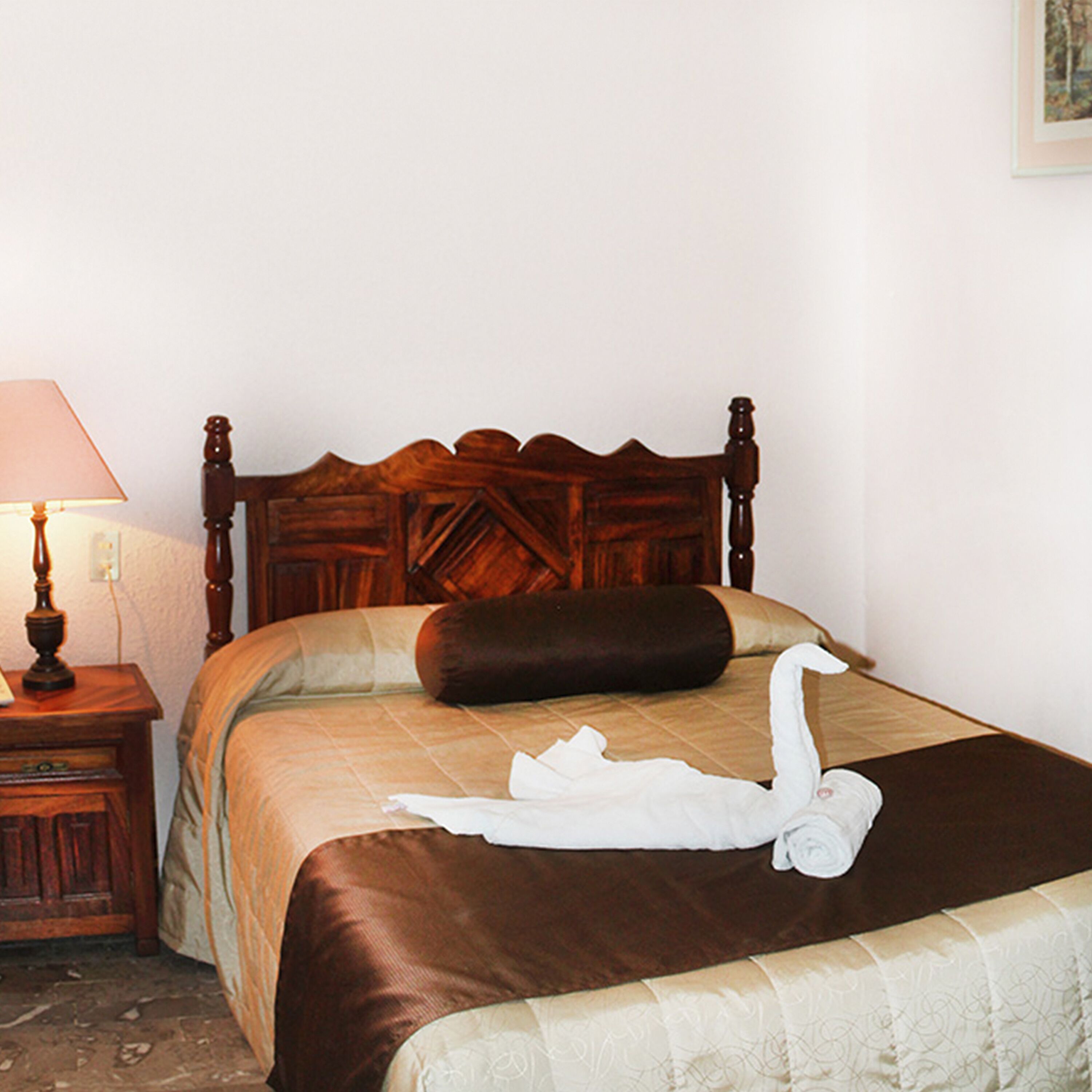 A neatly made bed with a brown headboard, a white towel, and a brown pillow.
