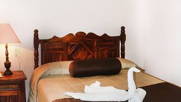 A neatly made bed with a brown headboard, a white towel, and a brown pillow.