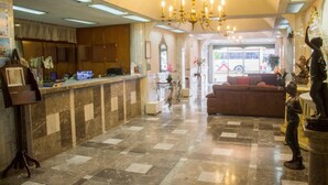 A lobby with a reception desk, a chandelier, a sofa, and a statue. - Hotel San Jorge (Tepic)