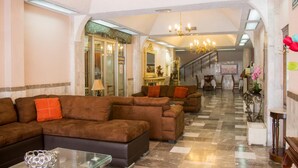 A spacious lobby with a checkered floor, a brown sectional sofa, and a glass coffee table. - Hotel San Jorge (Tepic)