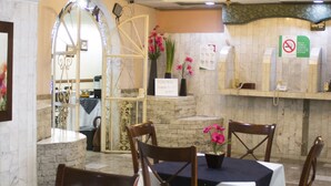 A restaurant interior with a stone wall, a chandelier, and a sign indicating a no-smoking policy. - Hotel San Jorge (Tepic)