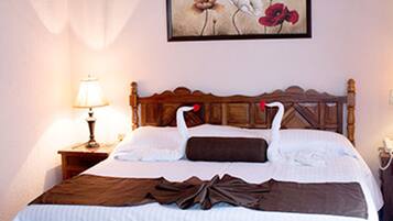A neatly made bed with a wooden headboard, a bedside lamp, and a floral artwork on the wall.