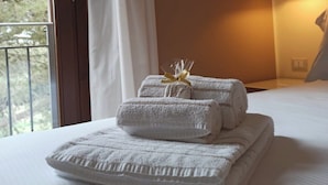 Una habitación de hotel con una cama, una ventana con cortinas y una lámpara de noche.
