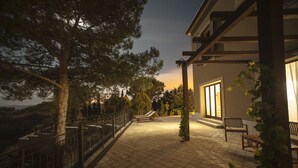 Un espacio de patio al aire libre con piso de baldosas, una pérgola de madera y un banco.