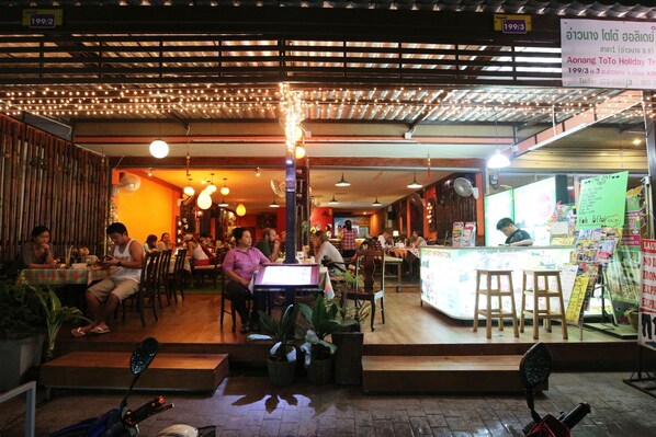 An indoor restaurant with tables and chairs, a counter, and hanging lights.