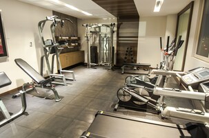 Un gimnasio con diversos equipos de ejercicio, incluyendo cintas de correr, máquinas de pesas y pesas libres.
