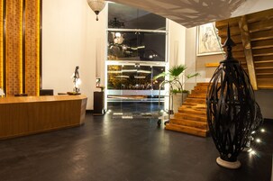 Un área de recepción moderna con un mostrador de madera, una división de vidrio y una escalera con escalones de madera.