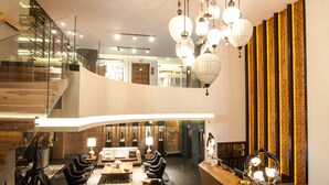 A modern hotel lobby with a curved reception desk, seating area, and a staircase leading to an upper level. - Square Small Luxury Hotel - Nuevo Consulado (Guadalajara)