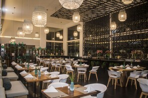 Un restaurant doté de nombreuses tables, de chaises et de luminaires suspendus.