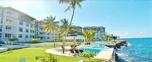 A resort with a pool, palm trees, and ocean views.