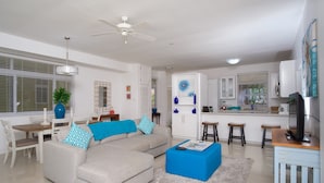 A modern living room with a sofa, coffee table, and dining area. - Whispering Seas (Tower Isle)