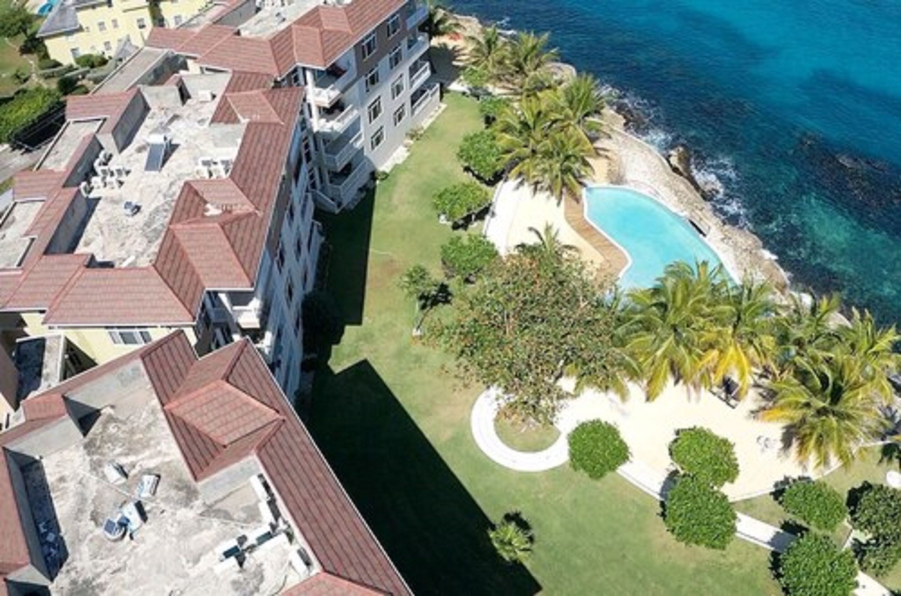 Vue aérienne d’un hôtel comprenant plusieurs bâtiments, une piscine et des palmiers.