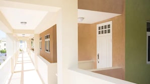 A corridor with a white ceiling, beige walls, and a green wall on the right. - Whispering Seas (Tower Isle)