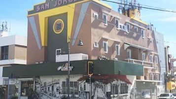 Un hotel llamado "San Jorge" con una fachada distintiva en amarillo y marrón, una escalera visible que lleva a la entrada y un mural en la parte exterior del edificio.
