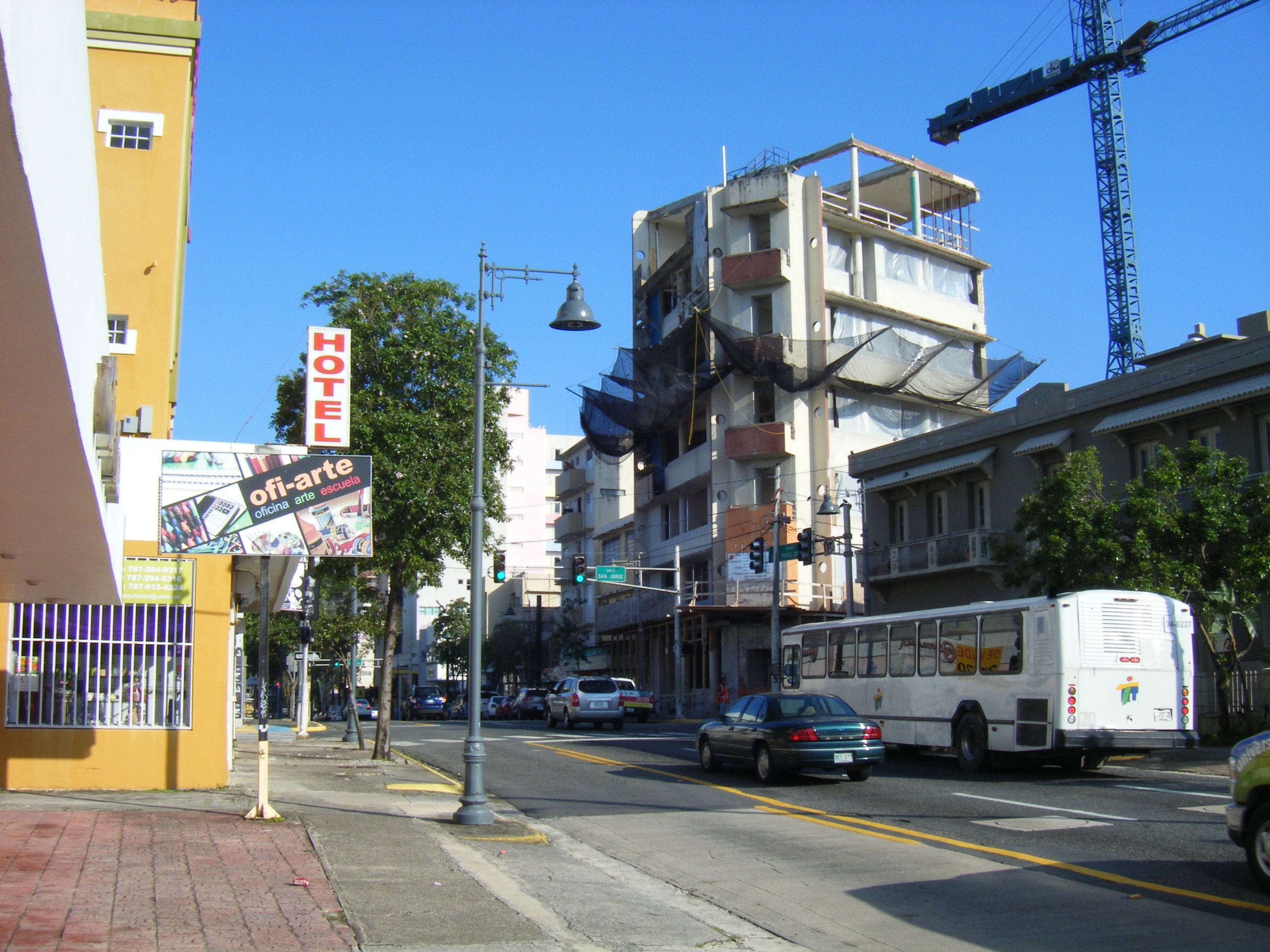 A street view with a hotel sign, a bus, and a building under construction.